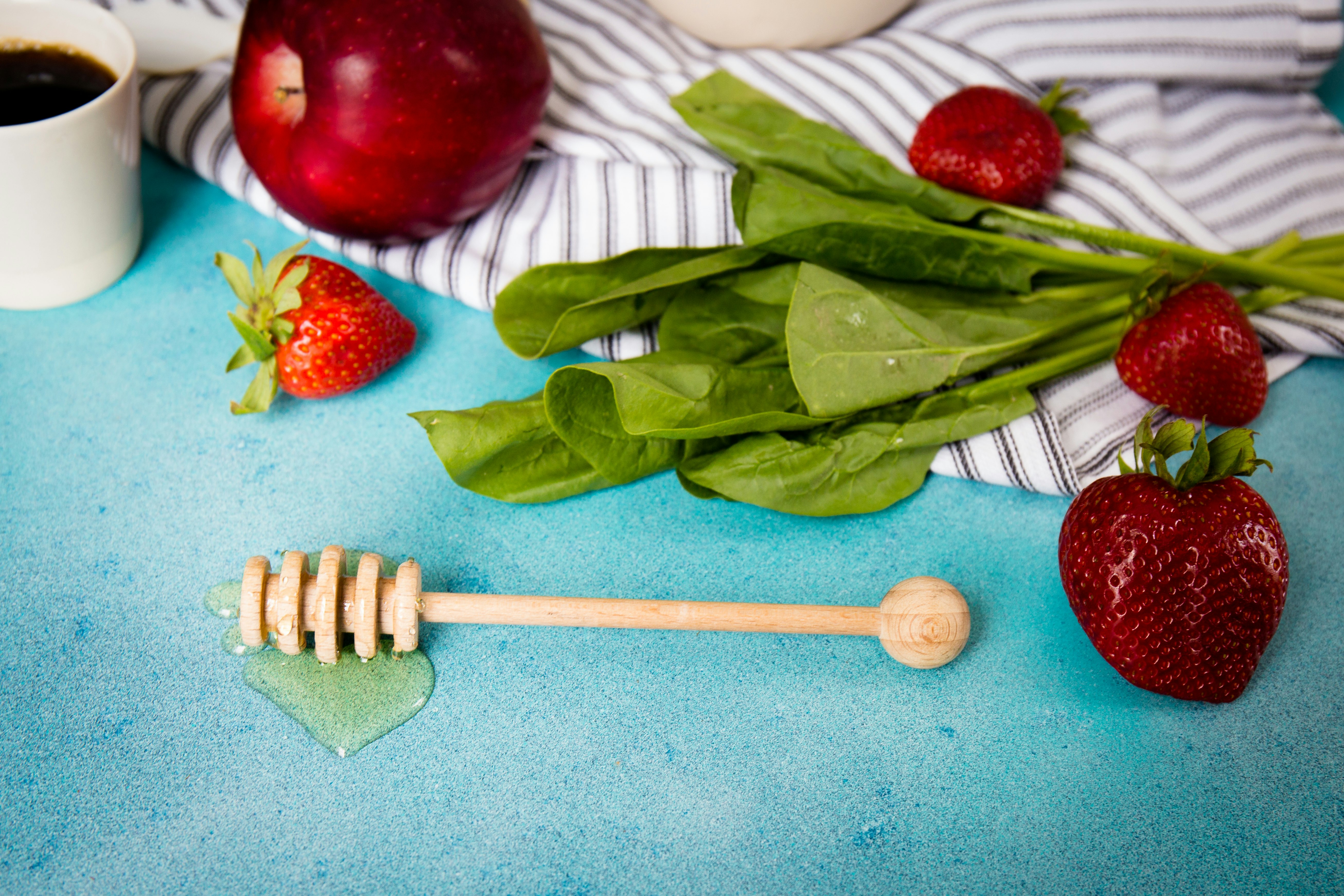 brown honey dipper beside strawberries and apple